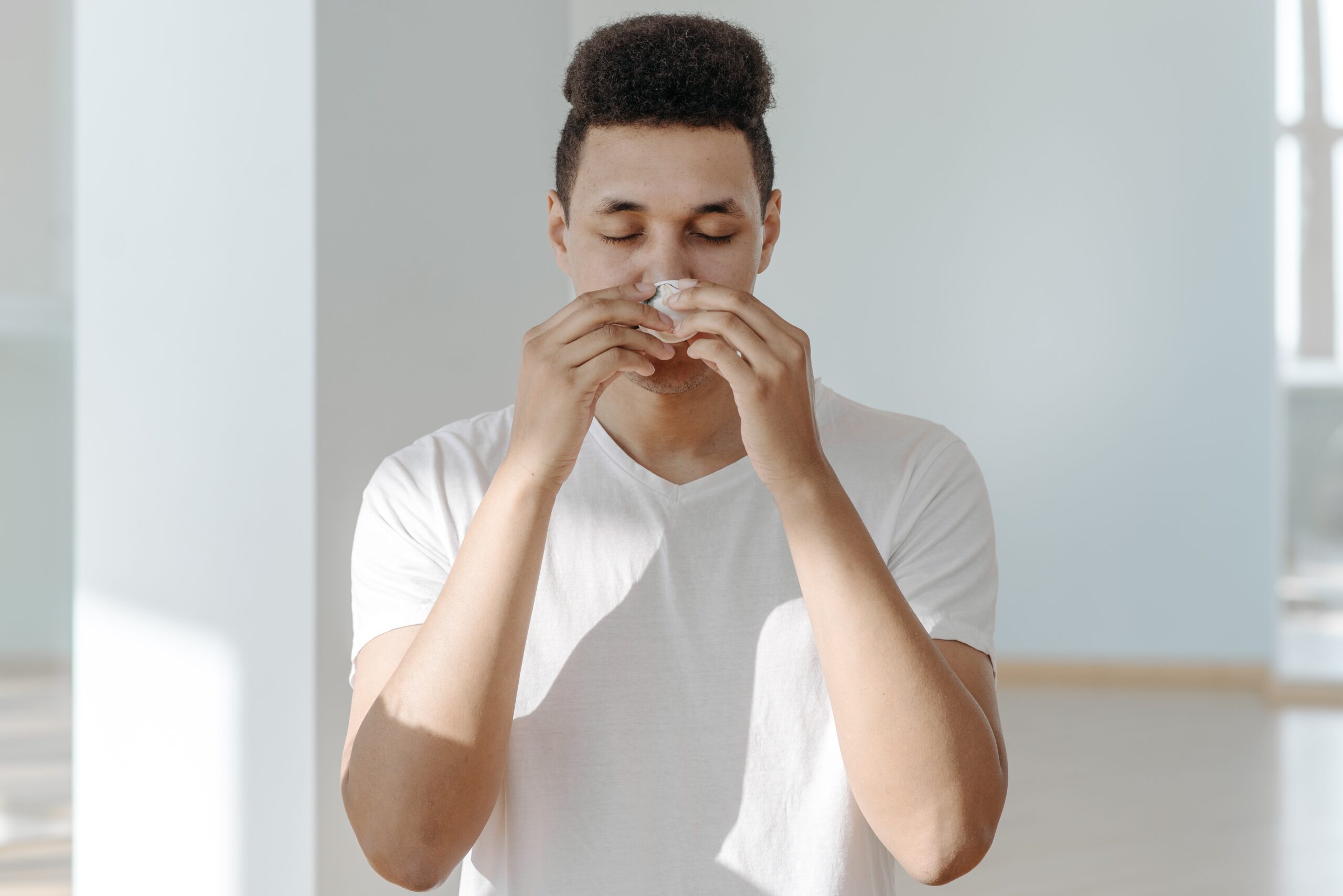 Person sneezing illustrating the importance of the “Stop Sneeze to Wheeze” initiative in combating Allergic Rhinitis and Asthma